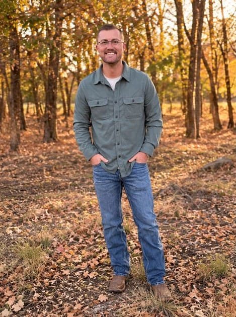 Caleb Christen, PE, standing in an autumn woodland